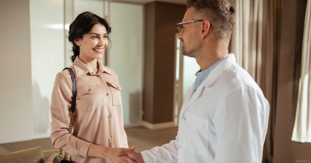 Woman shaking hands with a board-certified plastic surgeon in an office (models)