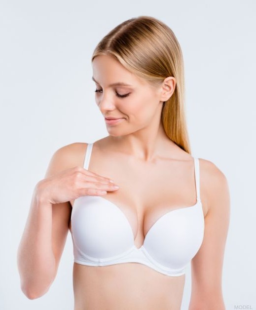 Woman admiring her breast implant removal results (model)